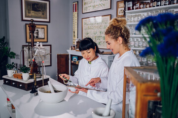 A Japanese pharmacist is making a traditional alternative cure while her assistant is showing her...