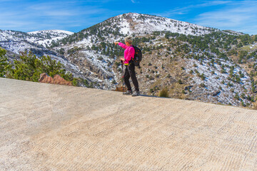 Woman hiker on the path pointing to the mountain