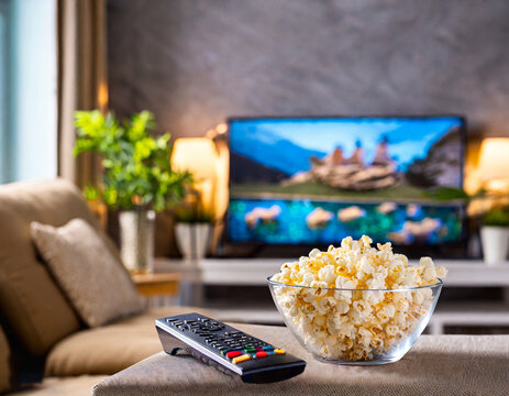 Palomitas en un bowl sobre una mesa con una television de fondo.