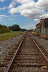 Fototapeta premium Railroad track leading to horizon next to abandoned warehouse