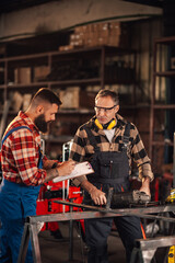 Experienced craftsman sharing new ideas from paper with his colleague.