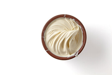 Wavy texture of yogurt cream in brown clay bowl isolated on white background. Top view with copy...