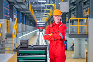 Portrait of professional technician worker stand with arm crossed and look at camera with smiling in electrical or sky train factory workplace.