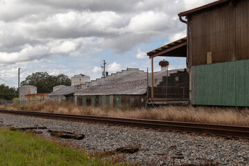 Fototapeta na wymiar Old train tracks next to abandoned warehouse and building with overcast sky
