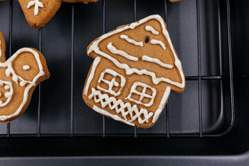 Homemade gingerbread cookies on tray on wooden background. Christmas and New Year celebration background. Close up of home baked cookies with icing.