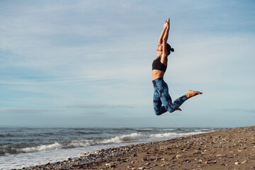 The girl is doing fitness on the seaside.