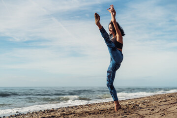 Obraz premium A beautiful brunette girl is dancing on the beach by the sea on the sand