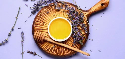 Rolgordijnen Wooden board, bowl of sweet lavender honey and dipper on lilac background, top view © Pixel-Shot