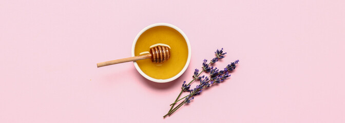 Bowl of sweet lavender honey, dipper and flowers on pink background, top view