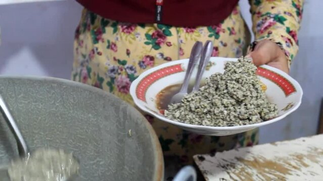 Prepare a bowl of Lontong Kupang or sea shells rice cake, a typical culinary food from East Java, Indonesia. A seller prepares fresh lontong kupang for customers.