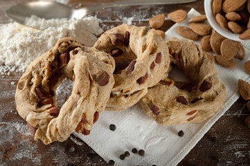 Neapolitan taralli, lard, pepper and almonds on wooden pastry board, close-up.