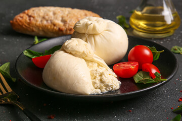Plate with tasty Burrata cheese on black background