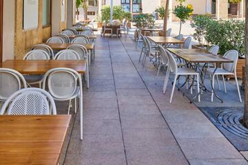 Tables and chairs of a small cafe without people on the street of the old town. Xabea, Spain.