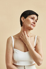 Minimal portrait of mature woman scratching neck with psoriasis spot suffering from skin condition