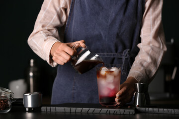 Female barista making cold brew coffee at table, closeup
