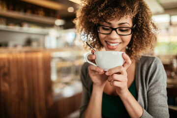 Happy young woman holding a cup of coffee in a cafe