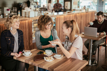 Three young multiracial women having coffee in a cafe