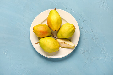 Plate with fresh pears on blue background