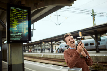 Man checking his phone while waiting at a transit station