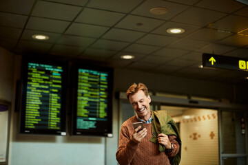 Man checking his phone while waiting at a transit station