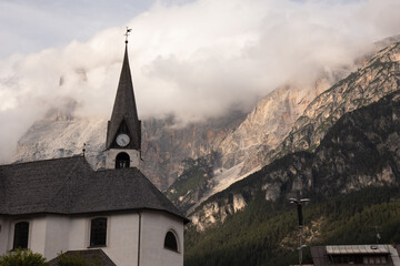 Fototapeta na wymiar Italian church beneath Dolomites' majesty
