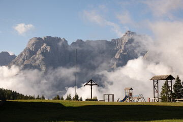 majestic mountains, clouds, and a playground blend into a captivating dolomites landscape