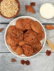 Freshly baked homemade oatmeal cookies with chocolate chips and gluten free nuts with ears on concrete background,modern bakery and grain food concept.Healthy breakfast with ingredients,top view