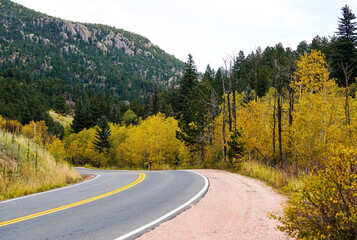 A winding road runs through Golden Gate Canyon State Park in Colorado with changing Aspen trees...