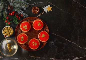 Christmas and New Year's dishes, a set of canapes for the festive table. Plate with tartlets of pate and red salmon caviar on a concrete table,