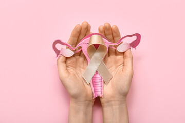 Woman with beige ribbon and paper uterus on pink background. Cancer awareness concept - obrazy, fototapety, plakaty