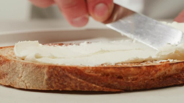 American sandwich, spreading butter cream cheese, chef cooking Famous thick cut sous vide beef sandwich on restaurant cafe kitchen. Bread with curd cheese. Studio shot close up.