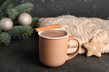 Cup of tasty Christmas cocoa with cinnamon on black background
