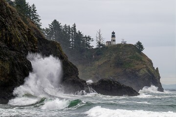 Fototapeta na wymiar waves crash on the rocks near a lighthouse
