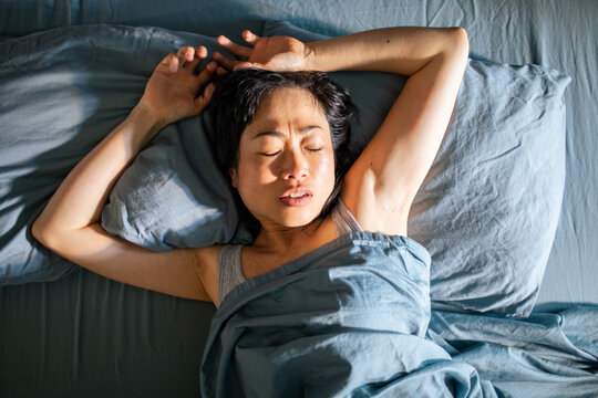 Young Asian woman sleeping in her bed at home
