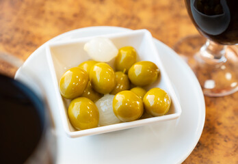 Pickled tasty green olives with pits and onions