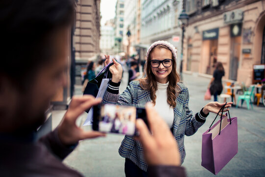 Attractive young woman getting her picture taken by her boyfriend while shopping in the city