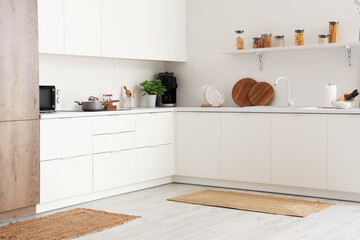 Interior of light kitchen with counters and wicker carpets