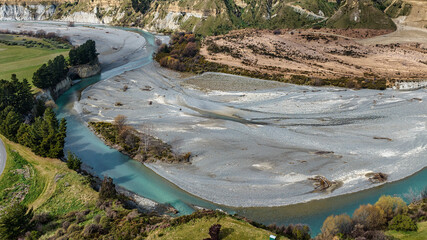 The blue water of the Awatere river flowing through agricultural farmland in a rural valley