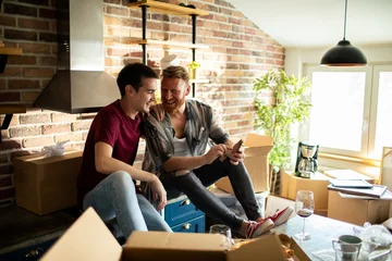 Foto op Plexiglas Happy young gay couple using a smartphone in the kitchen after moving in © Vorda Berge