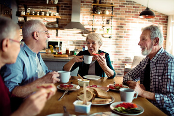 Group of elderly friends having breakfast together at home - obrazy, fototapety, plakaty