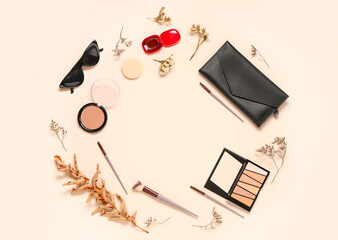 Frame made of makeup products, accessories and dry twigs on beige background