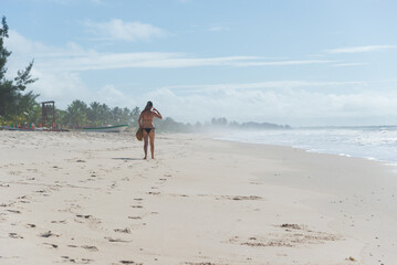A Caucasian woman walking on the sands of a tropical beach in northeastern Brazil.
