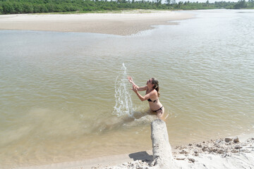 Beautiful woman in a bikini in a river throwing water into the air. Person on vacation and travel.