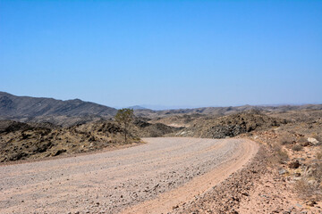 A deserted stony road in the hot desert foothills under a bright blue sky