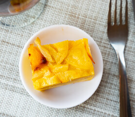 Traditional Spanish potato tortilla square piece served on white plate.