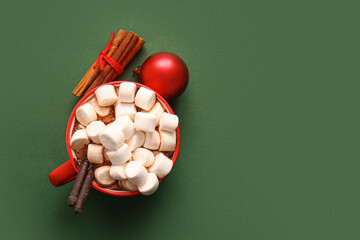 Cup of hot cocoa with marshmallows and cinnamon on green background