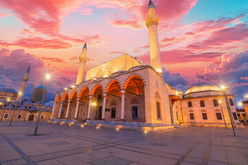 Selimiye Mosque in Konya, Turkey, bathes in the warm hues of sunset, its elegant domes and minarets silhouetted against the fading sky. The tranquil atmosphere deepens as the evening prayer begins