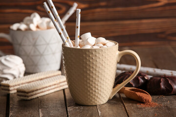 Cups of hot cocoa with marshmallows and sweet waffles on wooden background