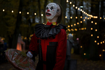 Fototapeta premium Halloween decoration, grinning clown standing on ghosts background in the forest