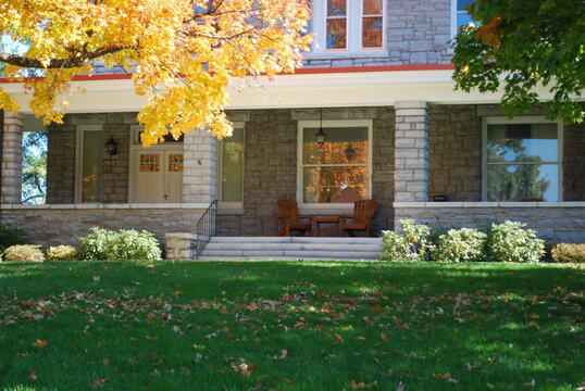 Bluestone Cottage Porch View Adirondack Chairs on Lush Green Grass Knoll Hill with Large Autumnal Yellow Leaf Tree Changing Colors